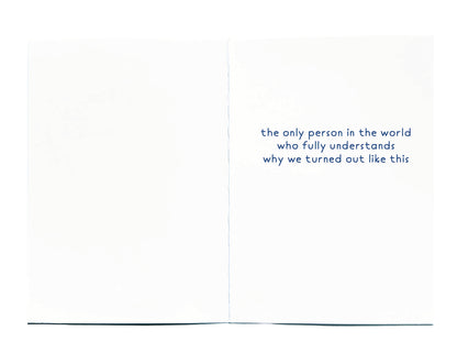 An open white greeting card with blue text on the right panel reading, 'the only person in the world who fully understands why we turned out like this.'.