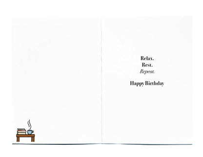 A birthday card shown open, with black text on the right reading 'Relax. Rest. Repeat. Happy Birthday, in left hand corner is a small illustration of a table with books and hot coffee in a mug on top
